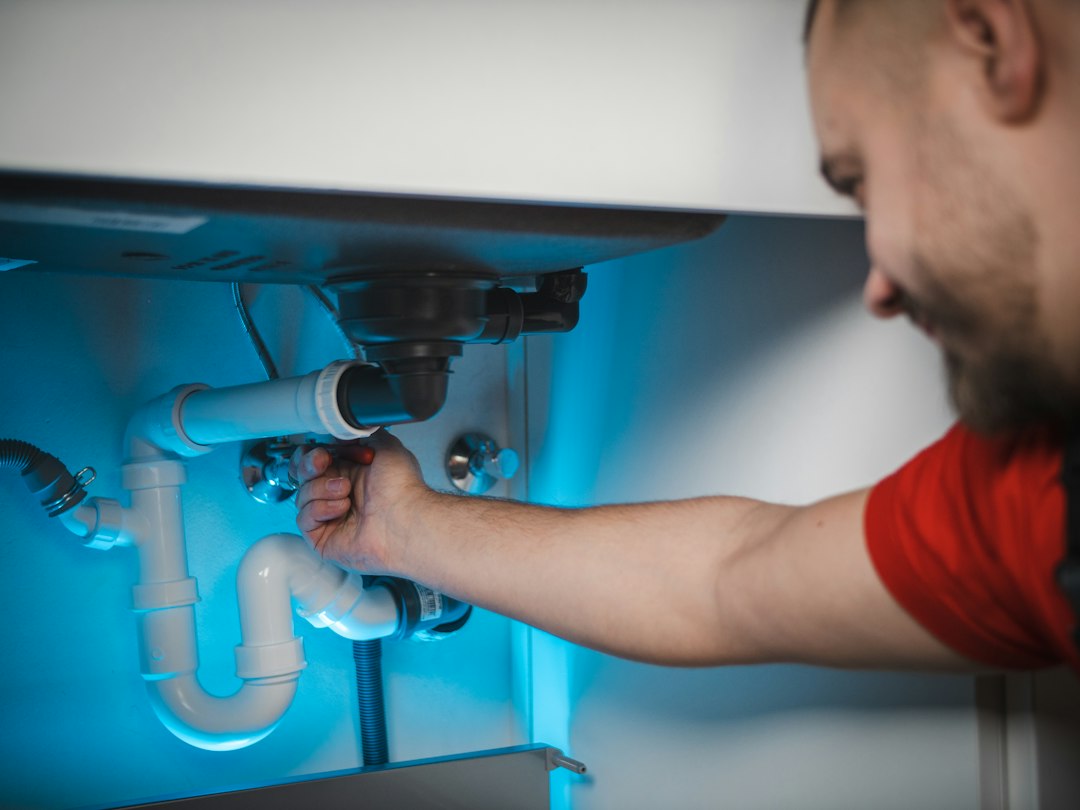 Technician working on accessible piping beneath a sink